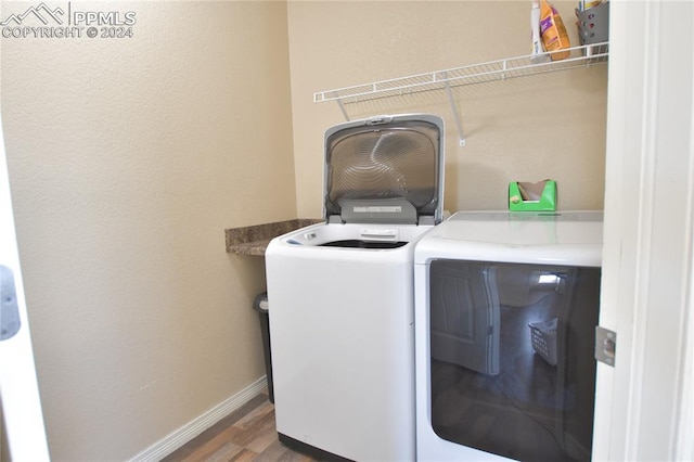 clothes washing area with washing machine and dryer and dark hardwood / wood-style flooring