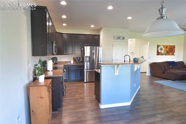 kitchen featuring appliances with stainless steel finishes, a kitchen island with sink, and dark wood-type flooring