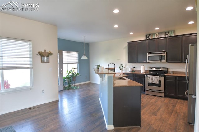 kitchen with sink, hanging light fixtures, stainless steel appliances, and dark wood-type flooring