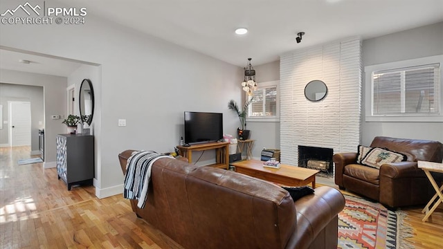 living room with a stone fireplace and light hardwood / wood-style flooring