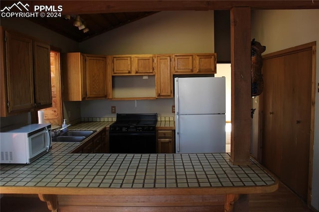 kitchen featuring kitchen peninsula, tile countertops, vaulted ceiling with beams, sink, and white appliances