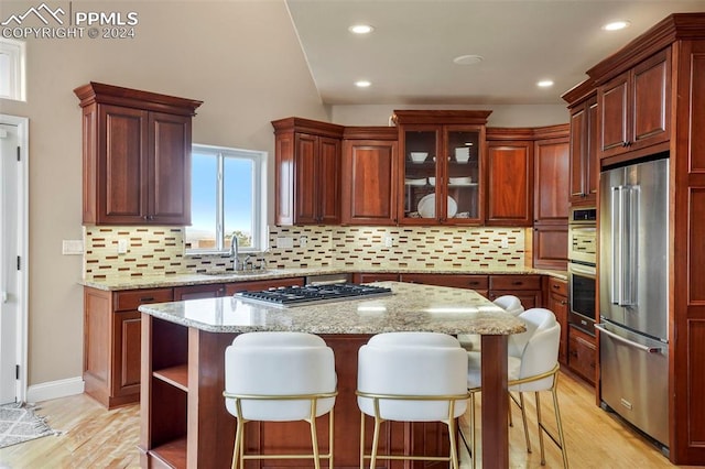 kitchen featuring appliances with stainless steel finishes, a sink, light wood-style flooring, and tasteful backsplash