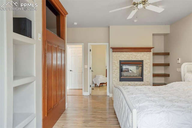 bedroom with light wood-type flooring, baseboards, ceiling fan, and a fireplace
