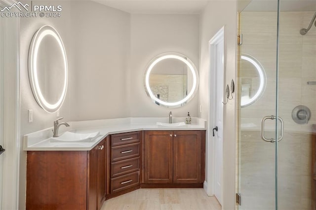 full bathroom featuring double vanity, a sink, a stall shower, and wood finished floors