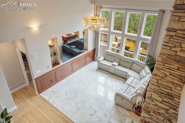 living area with visible vents, baseboards, a high ceiling, light wood-style flooring, and a notable chandelier