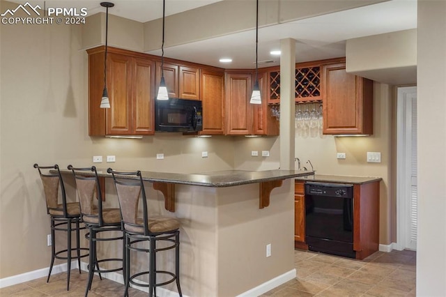 kitchen featuring dark countertops, a breakfast bar area, brown cabinetry, a peninsula, and black appliances