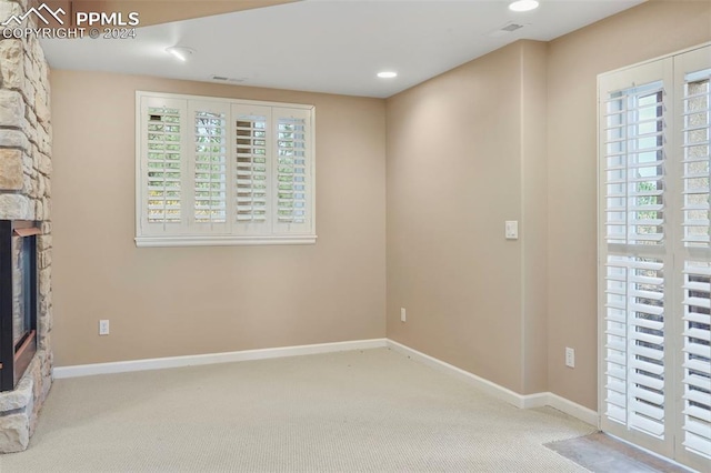 interior space with a stone fireplace, carpet, baseboards, and a wealth of natural light