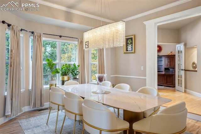 dining area with light wood-type flooring, baseboards, crown molding, and a chandelier