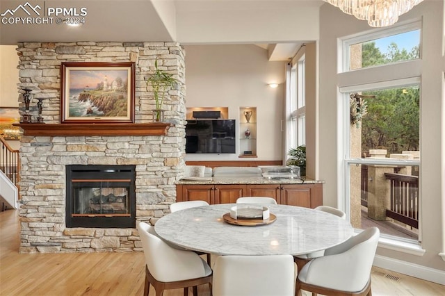 dining area with visible vents, a towering ceiling, a fireplace, light wood finished floors, and a notable chandelier