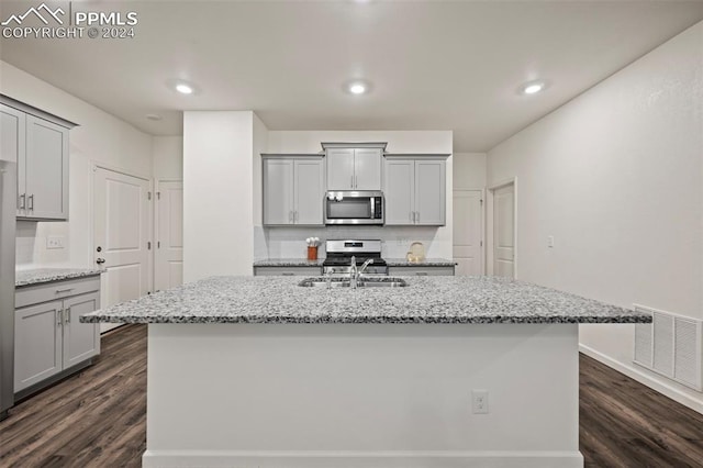 kitchen featuring appliances with stainless steel finishes, dark hardwood / wood-style flooring, an island with sink, and gray cabinets