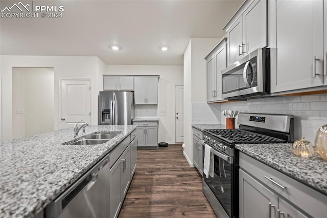 kitchen featuring dark hardwood / wood-style floors, sink, appliances with stainless steel finishes, light stone counters, and tasteful backsplash