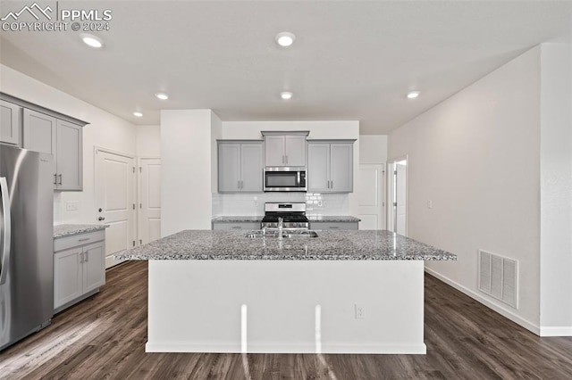 kitchen featuring dark wood-type flooring, stainless steel appliances, and a kitchen island with sink