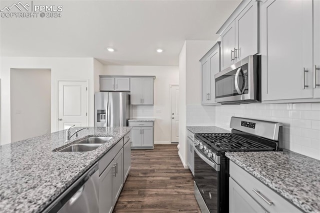 kitchen featuring tasteful backsplash, light stone countertops, dark wood-type flooring, sink, and stainless steel appliances