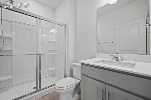 bathroom featuring vanity, a shower with shower door, toilet, and tile patterned flooring