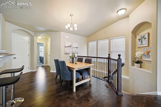 dining space featuring dark hardwood / wood-style flooring, lofted ceiling, and a notable chandelier