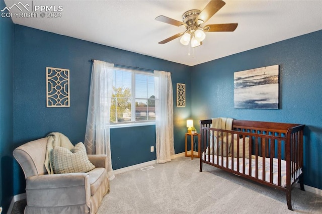 bedroom featuring light colored carpet, a crib, and ceiling fan