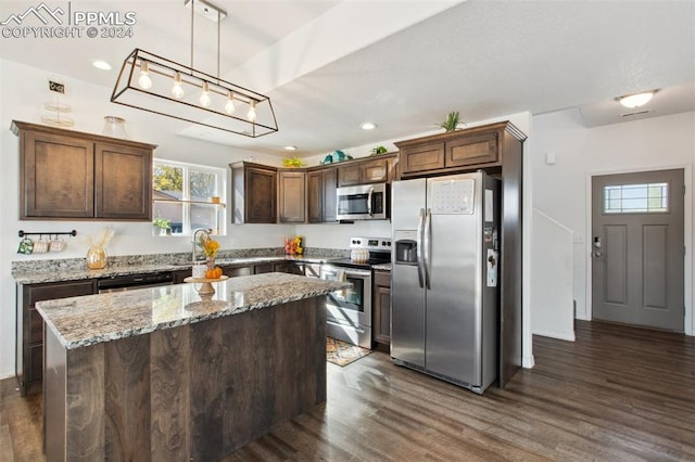 kitchen with a kitchen island, dark wood-type flooring, stainless steel appliances, light stone countertops, and pendant lighting