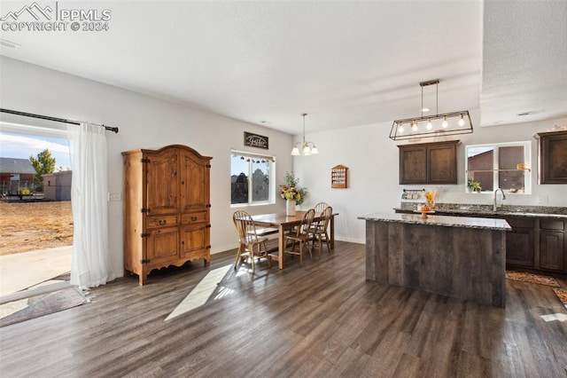 kitchen featuring dark brown cabinets, light stone countertops, decorative light fixtures, and dark hardwood / wood-style flooring