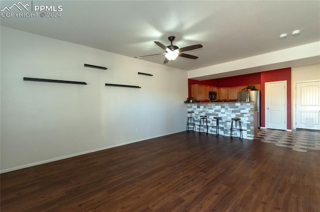 unfurnished living room featuring ceiling fan, indoor bar, and dark hardwood / wood-style flooring