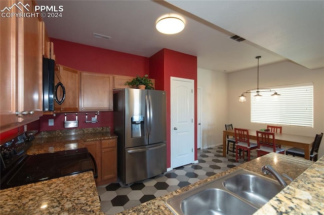 kitchen featuring sink, black appliances, hanging light fixtures, and dark stone countertops