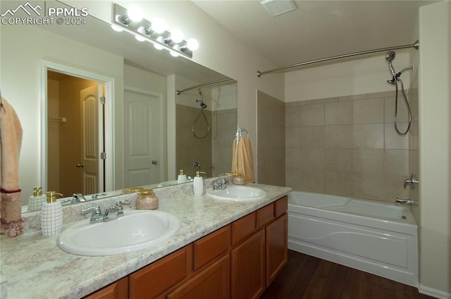 bathroom with tiled shower / bath, vanity, and wood-type flooring