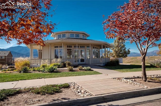 view of front of home with a front yard, a mountain view, and a porch