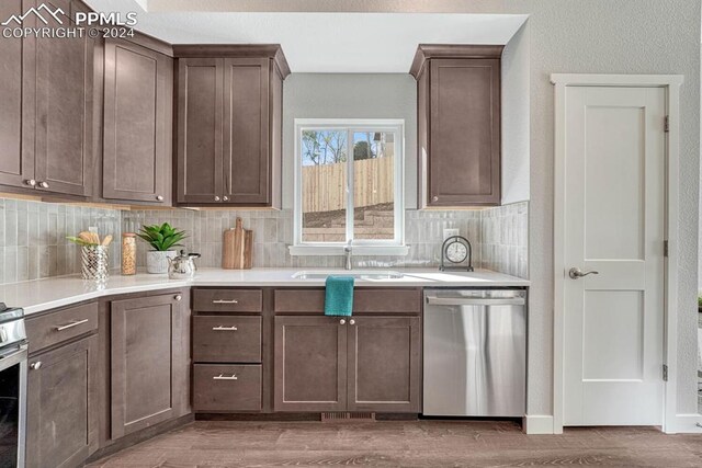 kitchen featuring sink, backsplash, light hardwood / wood-style floors, stainless steel appliances, and dark brown cabinetry