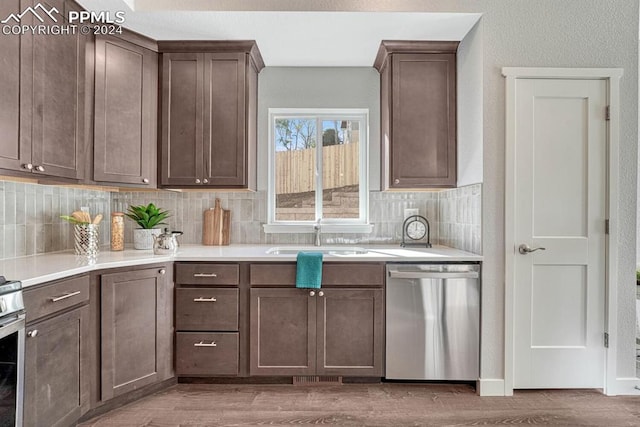 kitchen with hardwood / wood-style flooring, backsplash, sink, dark brown cabinetry, and stainless steel dishwasher