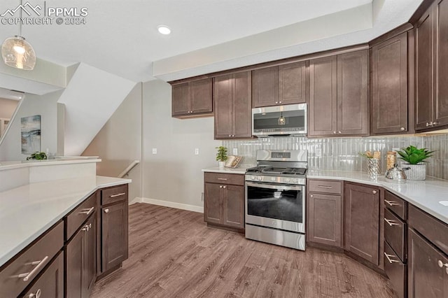 kitchen featuring tasteful backsplash, light wood-type flooring, dark brown cabinets, stainless steel appliances, and decorative light fixtures