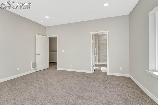 unfurnished bedroom featuring ensuite bathroom and light colored carpet