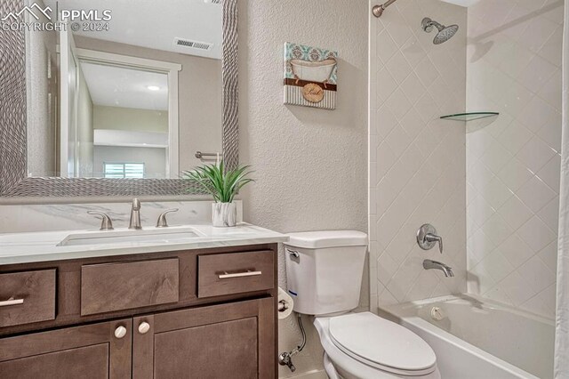 full bathroom featuring vanity, tiled shower / bath combo, and toilet