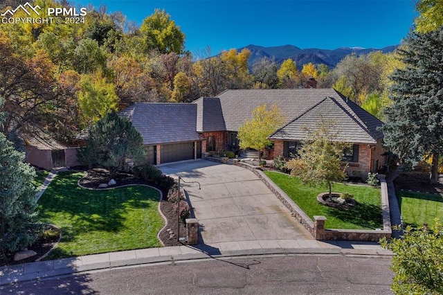 single story home with a mountain view, a front yard, and a garage