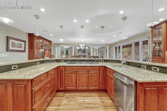 kitchen with stainless steel appliances, sink, light stone countertops, decorative light fixtures, and light wood-type flooring