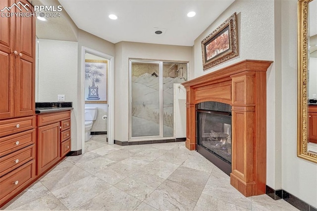 bathroom with vanity, toilet, a shower with shower door, and a fireplace