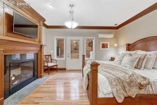 bedroom featuring an AC wall unit, crown molding, a textured ceiling, and light hardwood / wood-style floors