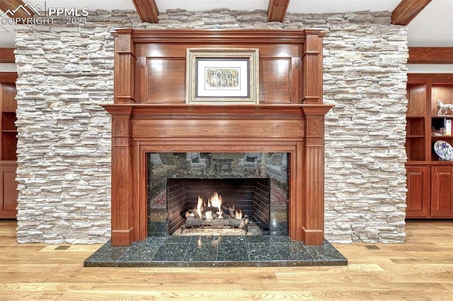 details with a tiled fireplace, beam ceiling, and wood-type flooring