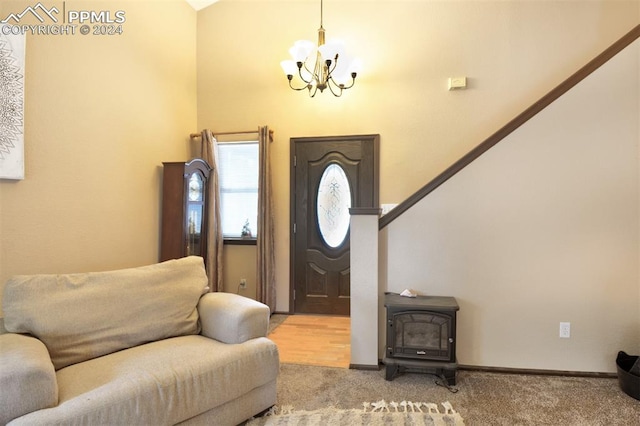 carpeted foyer entrance featuring a chandelier and a wood stove