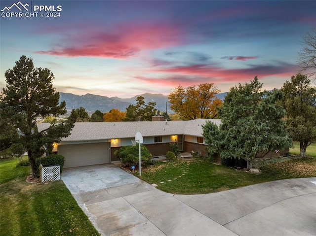 ranch-style house featuring a mountain view, a lawn, and a garage