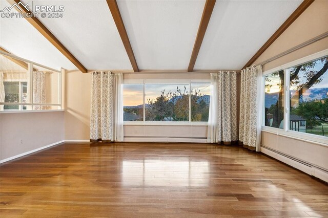 interior space with vaulted ceiling with beams, hardwood / wood-style floors, and a baseboard heating unit