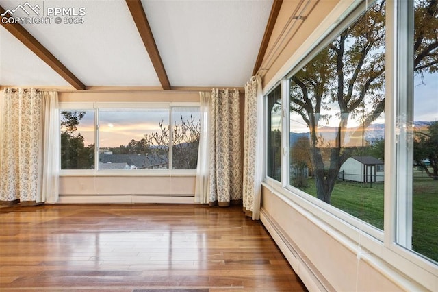 unfurnished sunroom with beam ceiling, a baseboard heating unit, and a healthy amount of sunlight