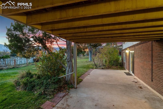 patio terrace at dusk featuring a lawn