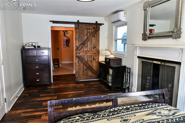 bedroom featuring an AC wall unit, dark hardwood / wood-style flooring, and a barn door