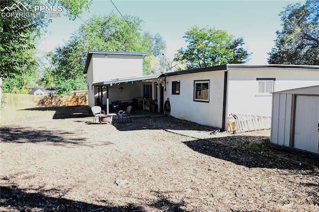 back of house with a patio area and a storage shed