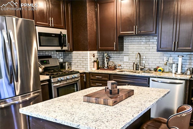 kitchen with sink, light stone counters, appliances with stainless steel finishes, and tasteful backsplash