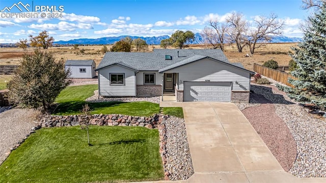 ranch-style house featuring a mountain view, a garage, and a front lawn