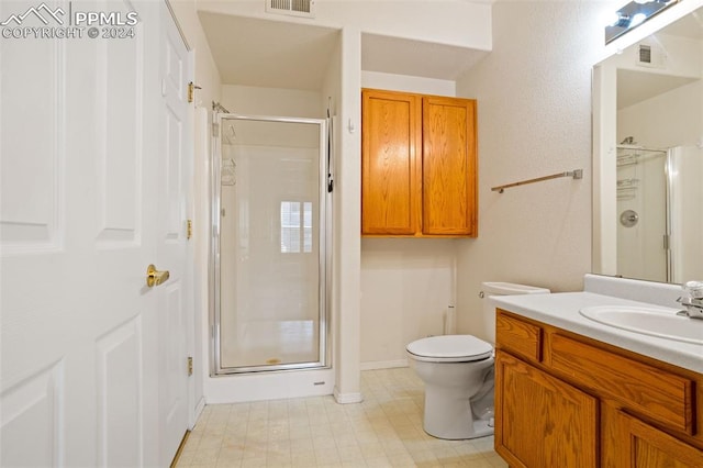 bathroom featuring a shower with door, vanity, and toilet