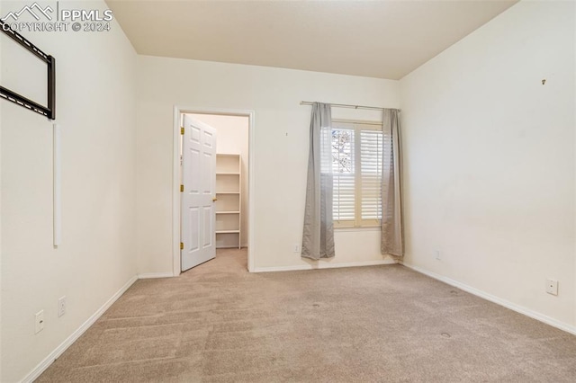 unfurnished bedroom with a spacious closet and light carpet