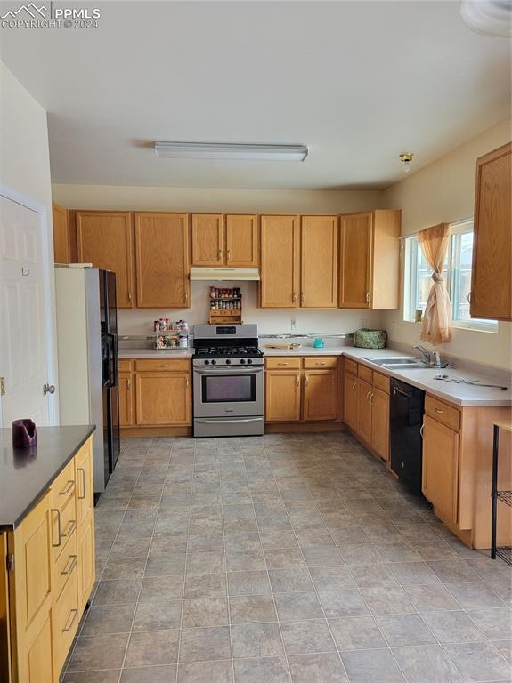 kitchen with black dishwasher, sink, light tile patterned flooring, white fridge, and stainless steel gas range