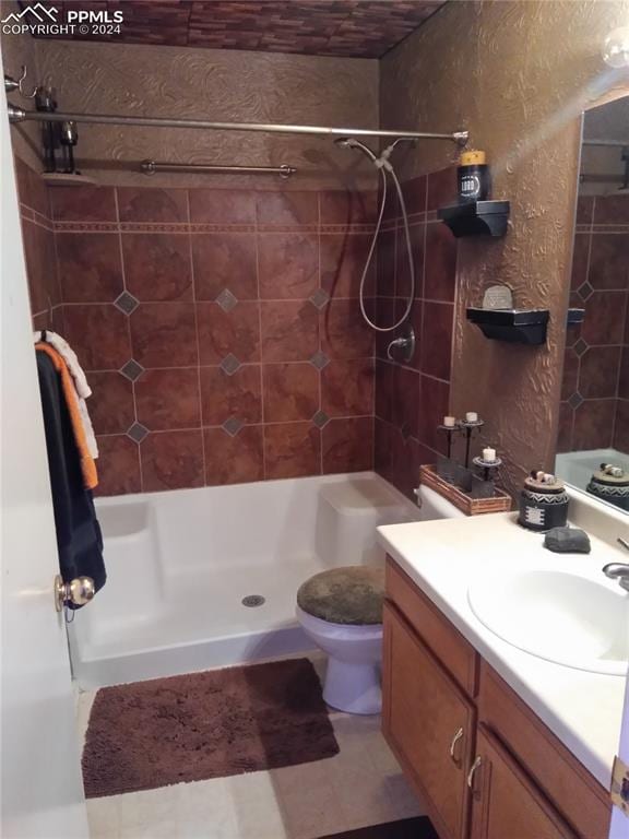 bathroom with toilet, vanity, and a tile shower