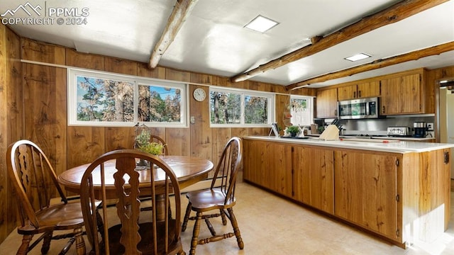 kitchen featuring kitchen peninsula, wooden walls, and beam ceiling